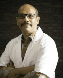 A professional doctor, Dr. Amrish Patodi, wearing glasses and a white coat, at Jain Surgical Hospital in Kota.
