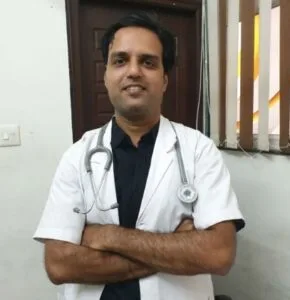 Dr. Ankur, a professional doctor from Jain Surgical Hospital, stands confidently in front of a door.
